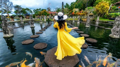 woman-standing-pond-with-colorful-fish-tirta-gangga-water-palace-bali-indonesia-min
